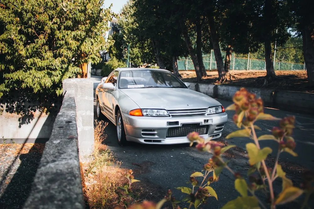Silver Nissan Skyline R32 GT-R on a tree-lined street
